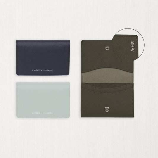 Labovarde Business Card Holder — Flat lay view of closed navy and clear blue cases next to an open etoupe holder showing custom engraving detail on a white background