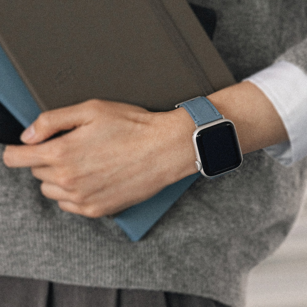 Labovarde Apple Watch Band in Dusty Blue — Close-up view of a wrist holding a Etoupe Diary and wearing the band