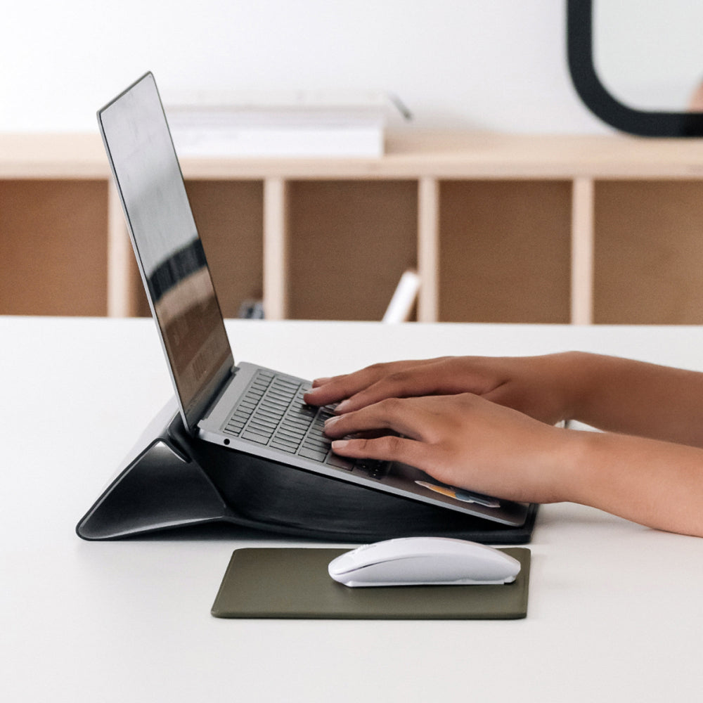 Labovarde Laptop Stand Case in Black — Side view of hands typing on an elevated laptop next to a mouse pad