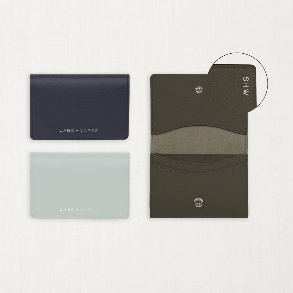 Labovarde Business Card Holder — Flat lay view of closed navy and clear blue cases next to an open etoupe holder showing custom engraving detail on a white background