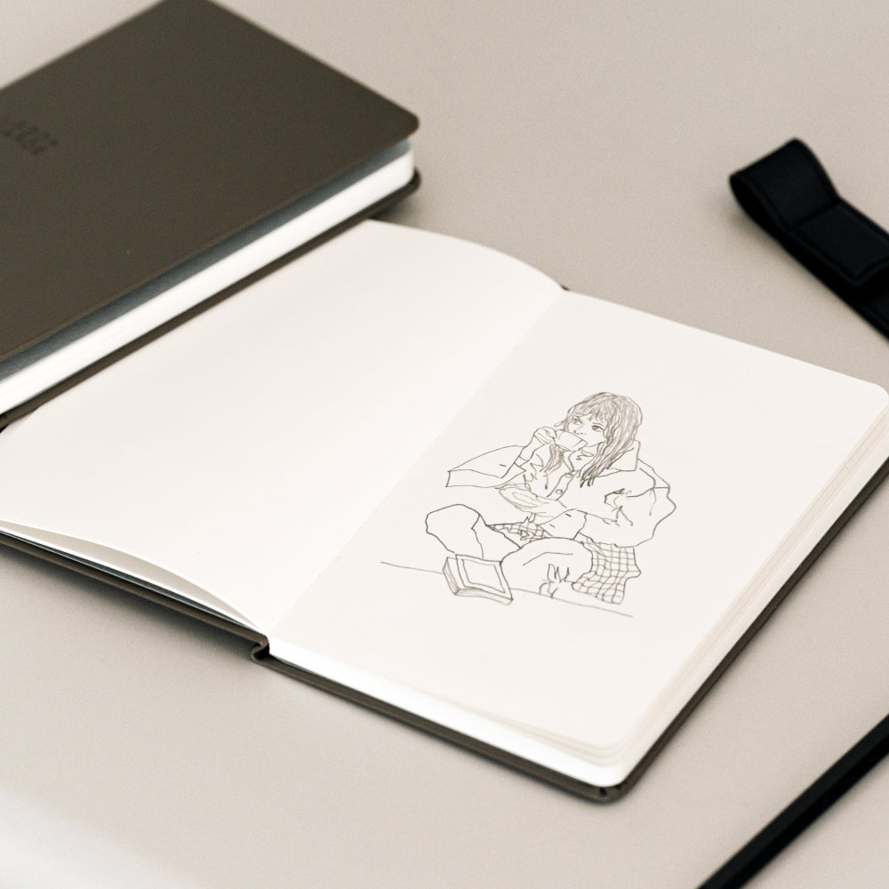 Labovarde Handy Note in Etoupe — Perspective view of an open note with a line drawing of a girl on a gray surface