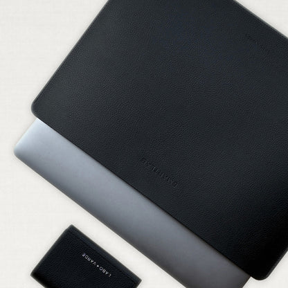 Labovarde Laptop Sleeve in Black — Flat lay view of a silver laptop inside the sleeve next to a small wallet