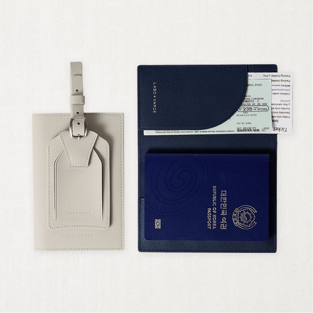 Labovarde Passport Case and Name Tag — Flat lay view of open navy Case with a passport and sand gray Tag