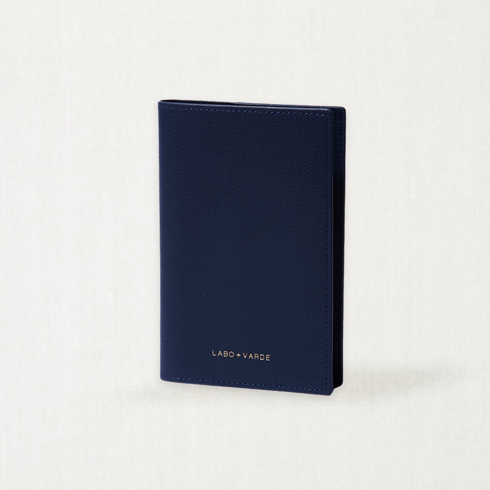 Labovarde Passport Case in Navy — Perspective view of the closed case standing on a minimalist textured white background