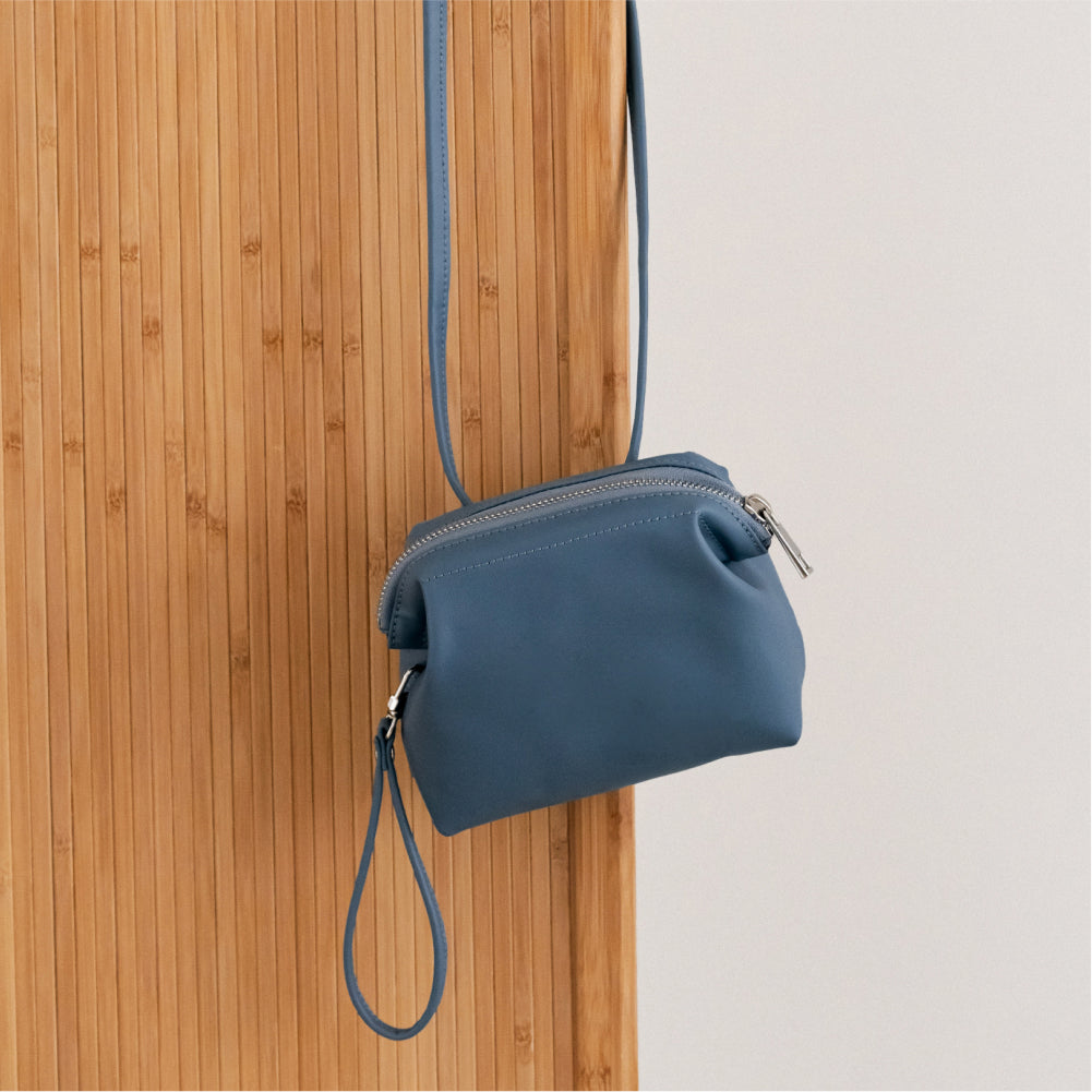 Labovarde Shell Pouch Bag in Pale-Blue — Close-up of the leather bag hanging on a wooden desk 