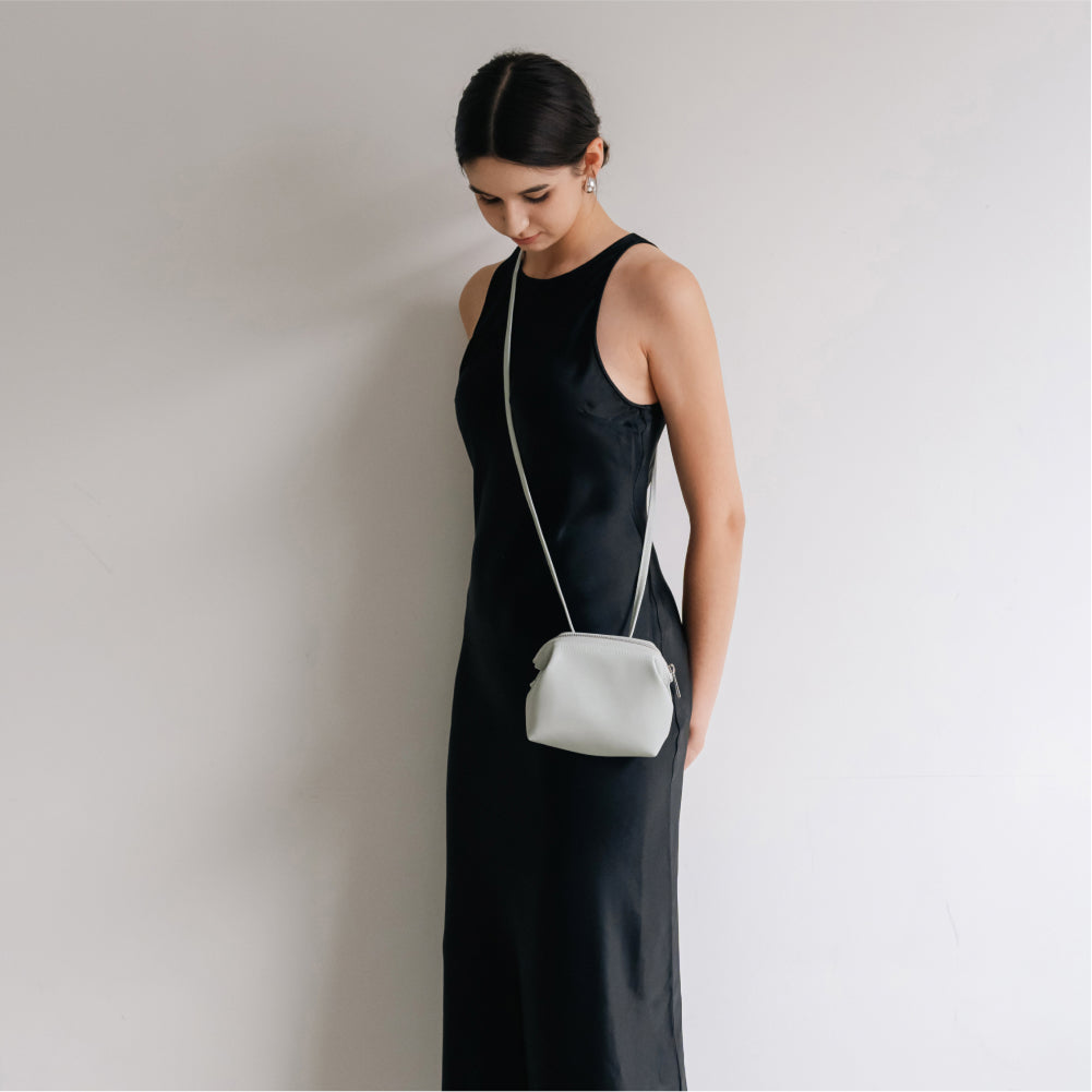 Labovarde Shell Pouch Bag in Light-Gray — Vertical shot of a woman in a black dress modeling the crossbody pouch