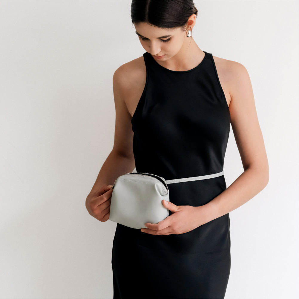 Labovarde Shell Pouch Bag in Light-Gray — Close-up of a woman in a black dress modeling the pouch as a fanny pack style